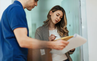 Low angle view of woman signing to delivery man while standing on a doorway