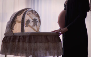 A pregnant woman standing in front of a bassinet